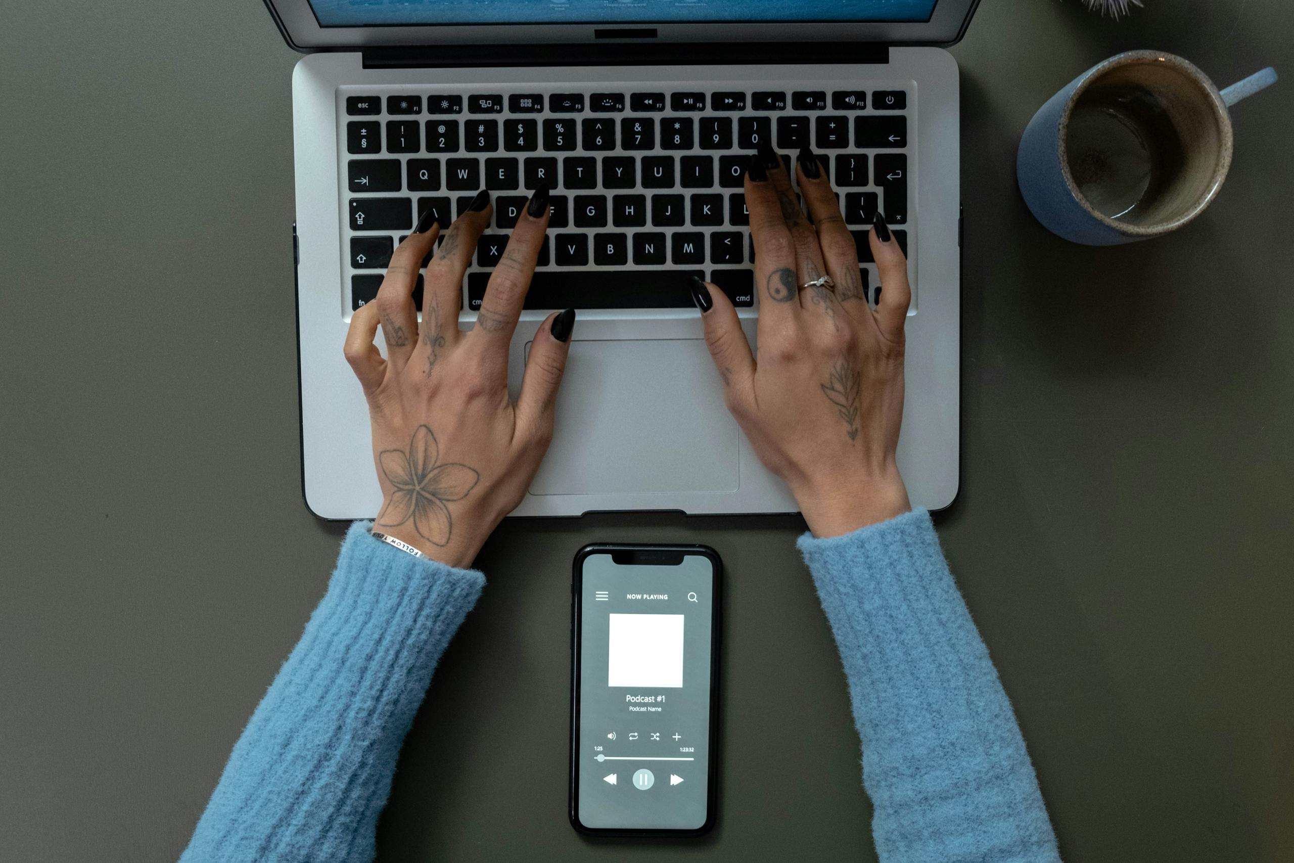 Overhead Shot of a Person Typing on a Laptop While Listening to a podcast